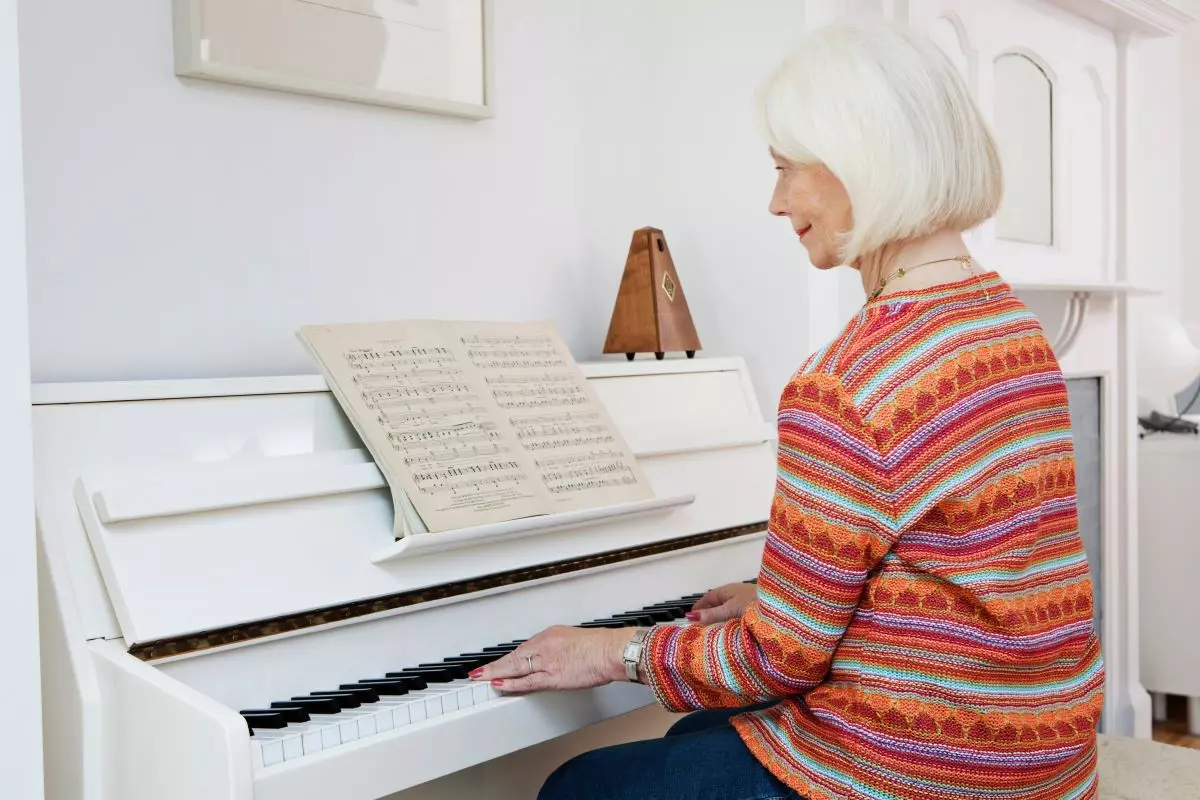 Senior woman practicing on a piano with a metronome